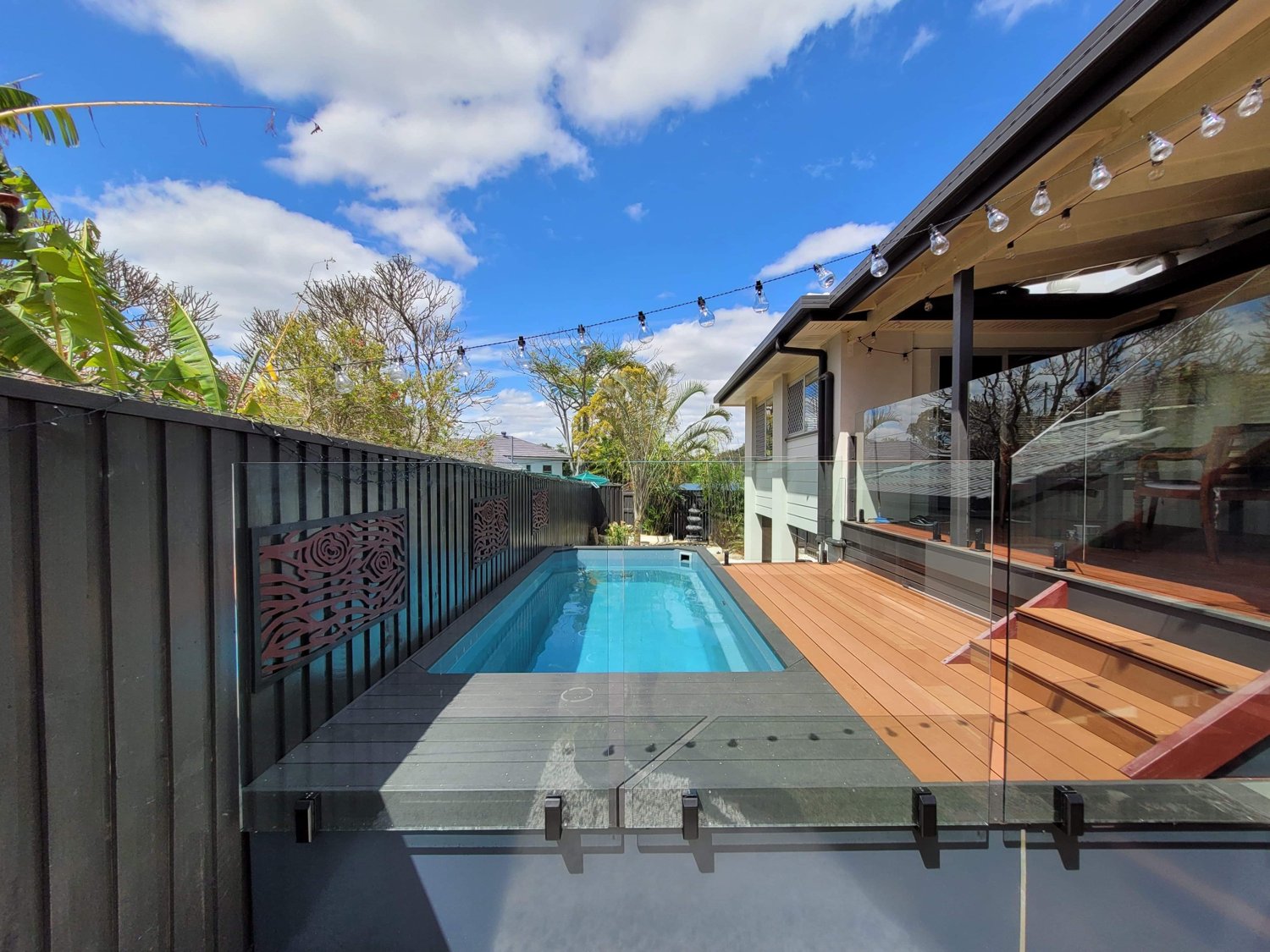 Self-standing fiberglass pool installed above ground with timber deck